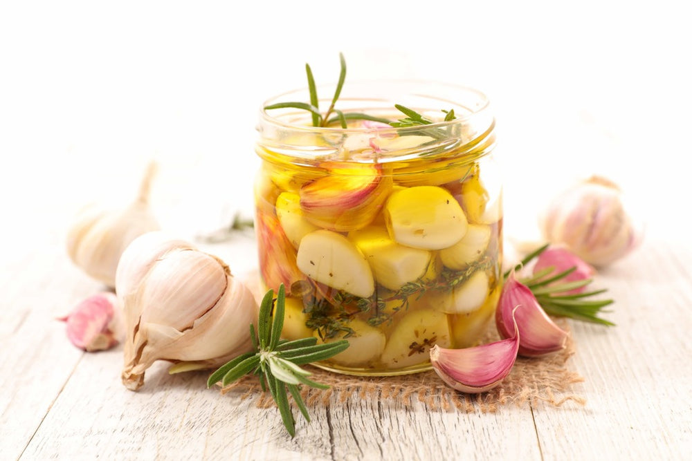Garlic confit in a jar with olive oil, rosemary, and thyme