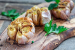 Roasted garlic on a cutting board with herbs